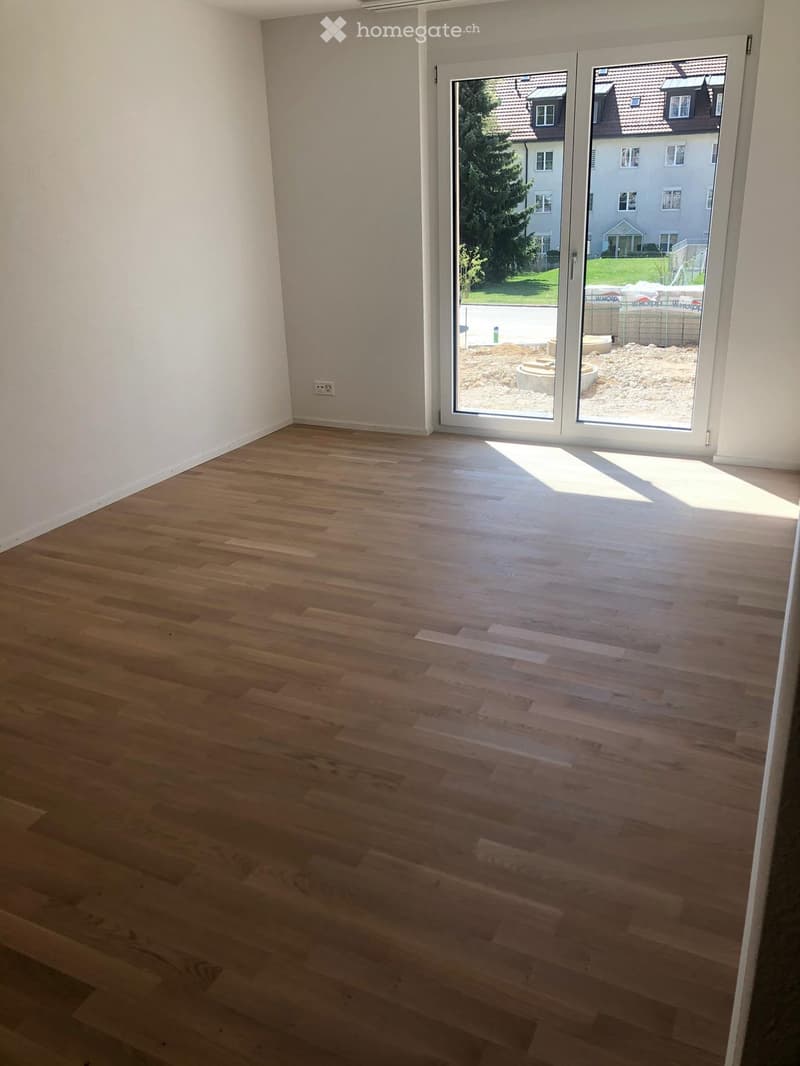 Empty room with light wooden flooring and large sliding glass doors leading to an outdoor area.