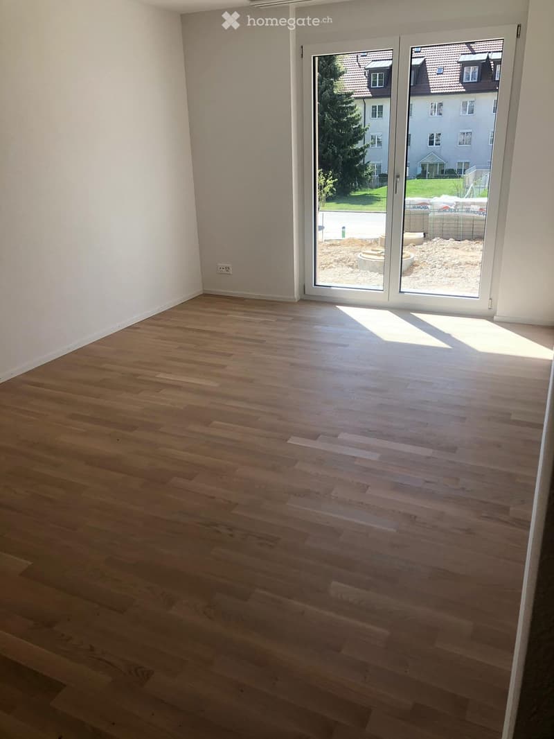 Empty room with light wooden flooring and large sliding glass doors leading to an outdoor area.