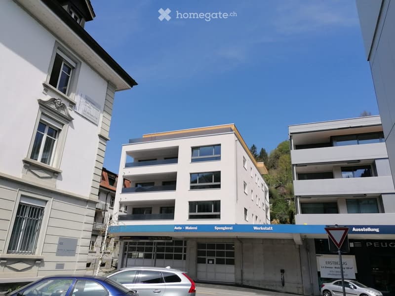 Modern apartment building with multiple floors, glass windows, and garage doors.