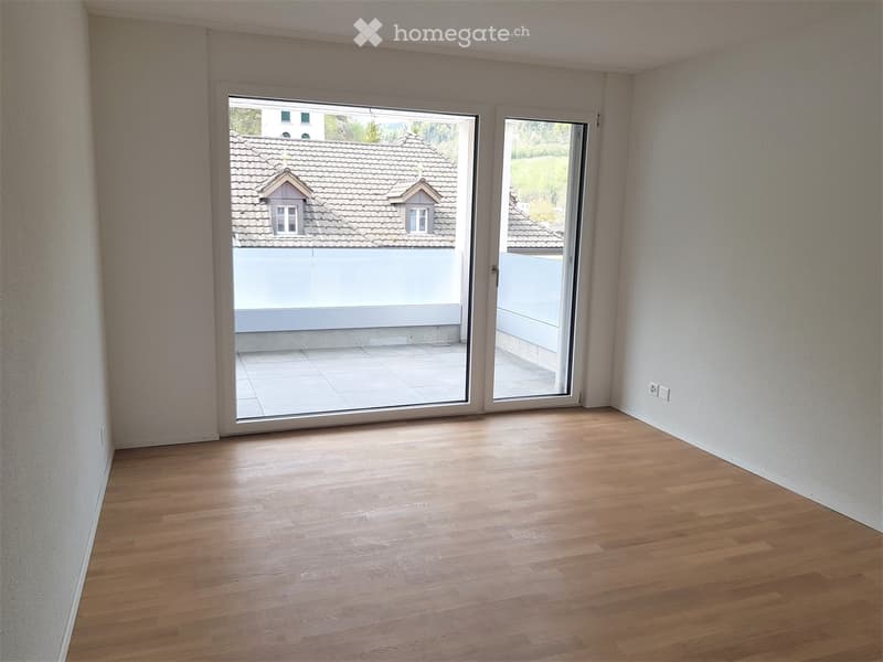 modern room with wooden floors, white walls, large sliding glass doors, glass balcony railing