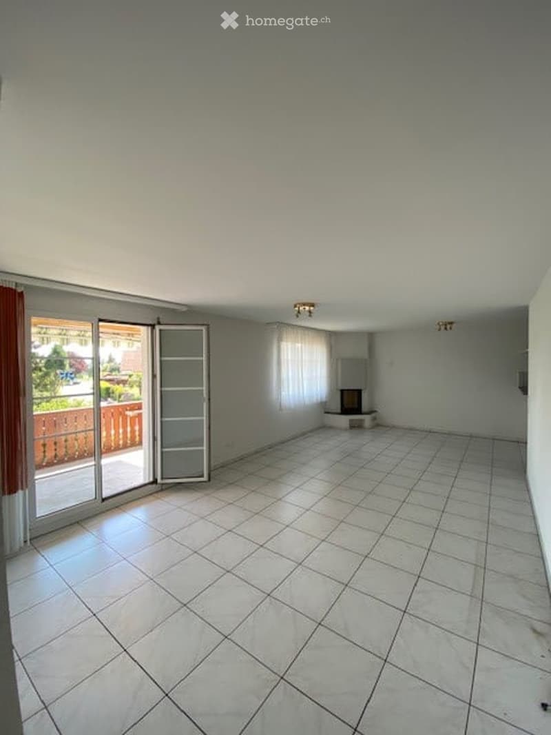 Empty room with tiled floor, large sliding glass door leading to a balcony, white walls, and a fireplace in the corner.