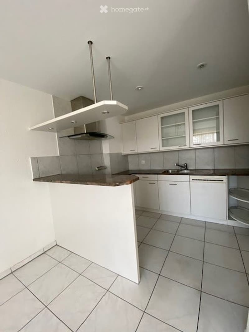 Modern kitchen with white cabinets, a central island, and a built-in dishwasher. The space features tiled flooring and a sleek, contemporary design.