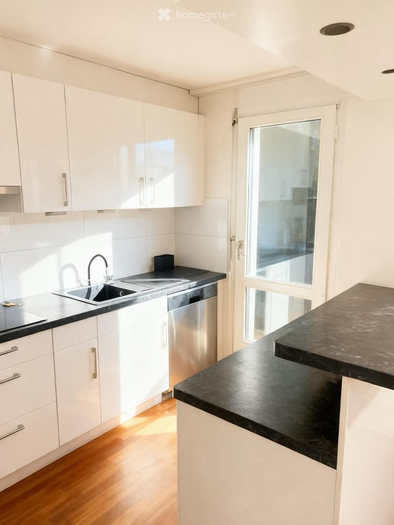 Modern kitchen with white cabinets, black countertops, a sink, and a dishwasher. Features a large window and wooden flooring.