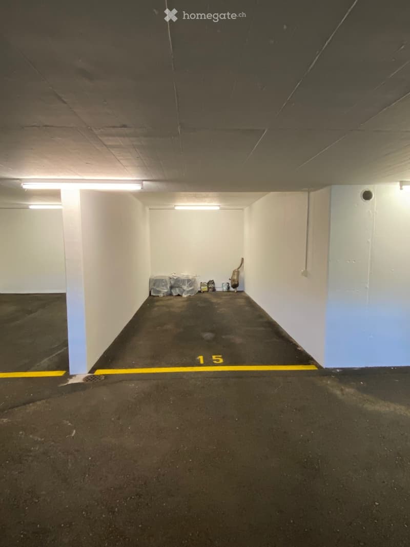 Underground parking space with numbered spot, white walls, and a fire extinguisher in the corner.