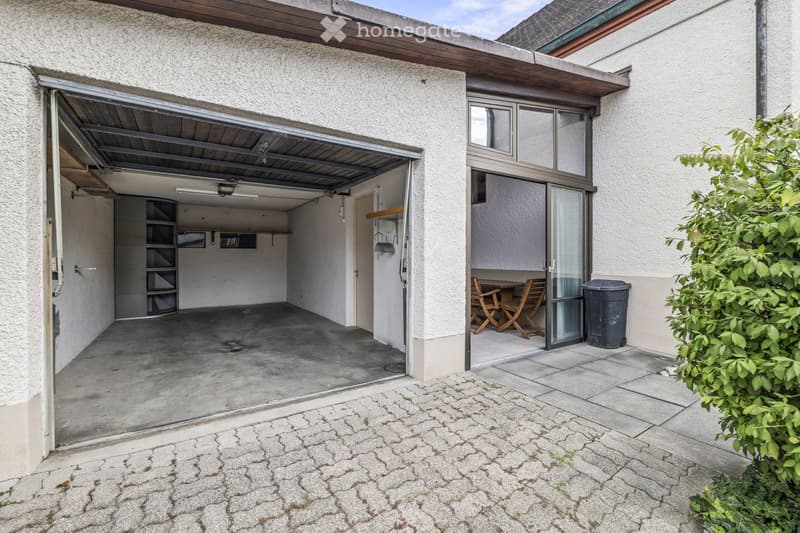 Garage with a concrete floor, metal shelving, and a small outdoor seating area with a table and chairs.