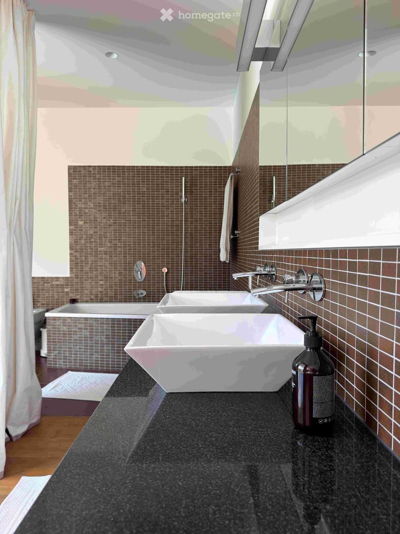 Modern bathroom with dark granite countertop, two white sinks, a bathtub, and a large mirror above the sinks.