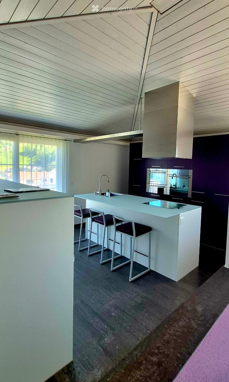 Modern kitchen with white cabinets, a central island, bar stools, and stainless steel appliances including an oven and sink.