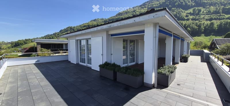 Spacious balcony with tiled flooring, white railings, and scenic mountain view in the background.