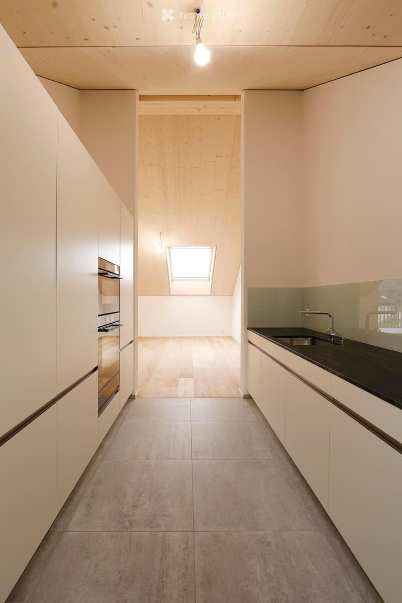 minimalistic kitchen with white cupboards, wooden floors, open to another room with window