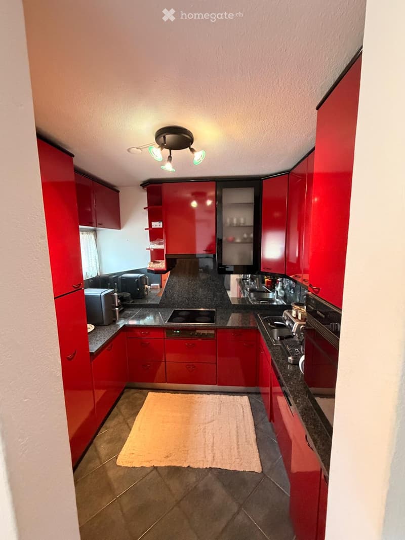 modern kitchen, red cabinets, black countertops, white appliances, tile flooring, sink, faucet, stovetop, microwave, dishwasher, toaster, coffee maker, and lamps