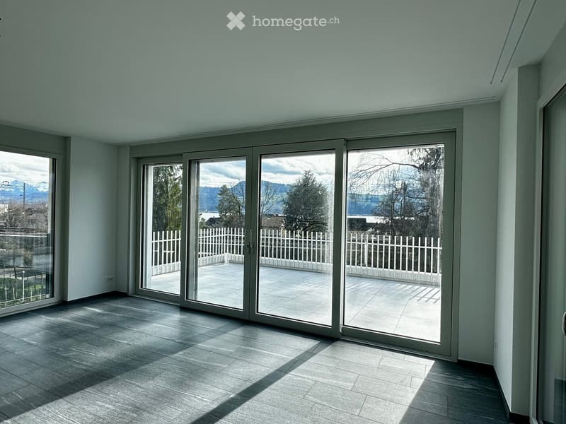 Empty room with large sliding glass doors leading to a patio, light-colored tiled floor, and white walls.