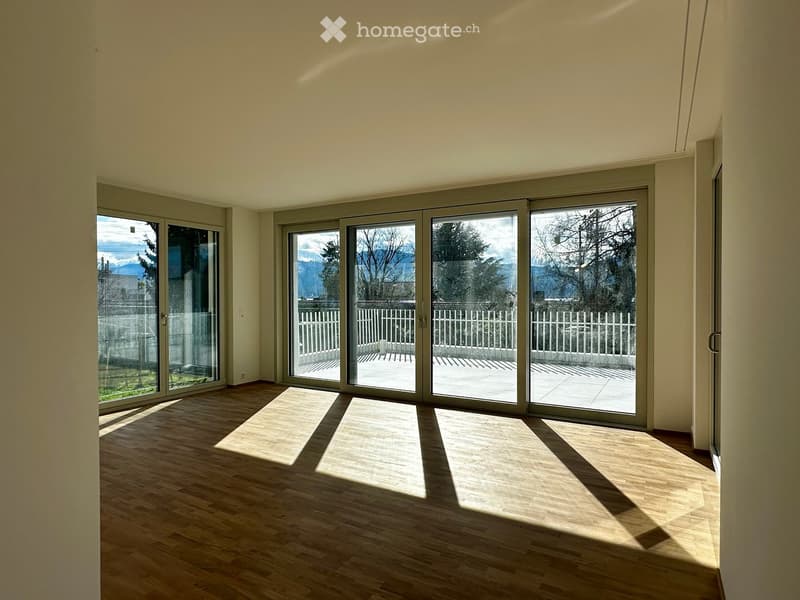 Empty room with wooden flooring and large sliding glass doors leading to a balcony or terrace area.