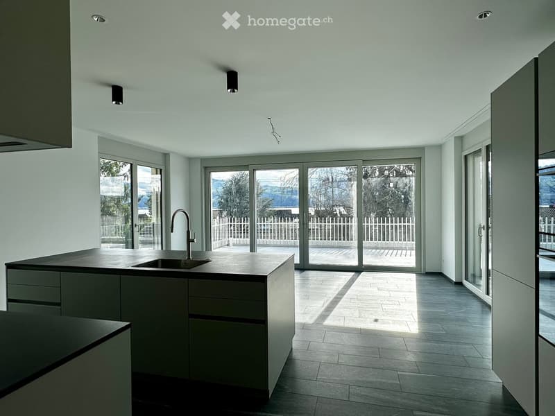 Modern kitchen with a central island, sink, and large sliding glass doors leading to an outdoor area.