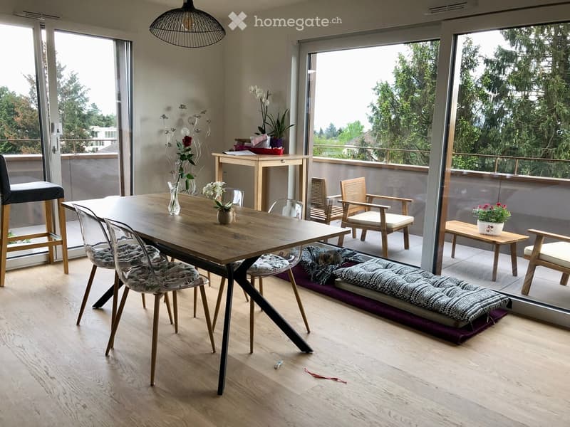 Modern dining area with wooden table, chairs, and a view of the balcony. Includes a small bench and decorative vases.