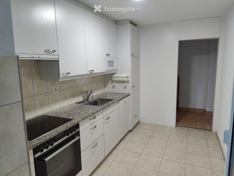 Modern kitchen with white cabinets, granite countertop, sink, oven, and microwave. Tile backsplash and tiled floor.