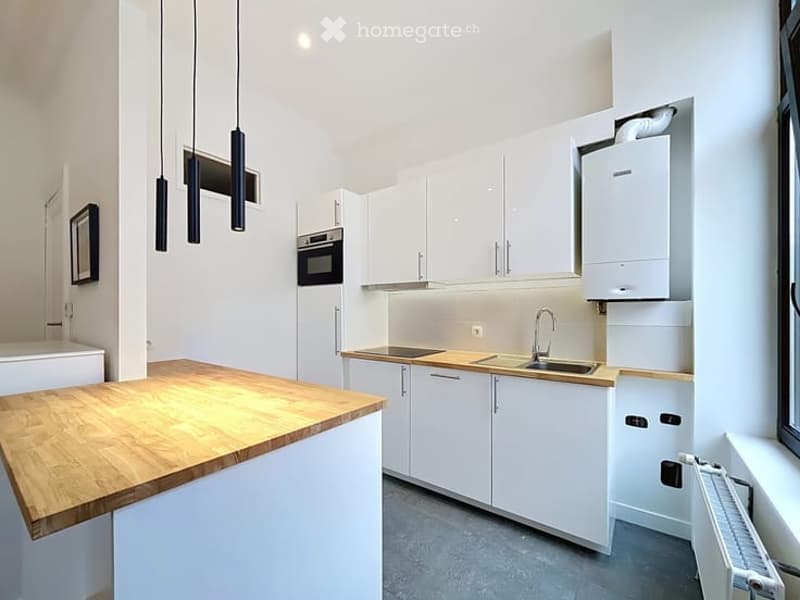 Modern kitchen with white cabinets, wooden countertop, stainless steel sink, and built-in oven.
