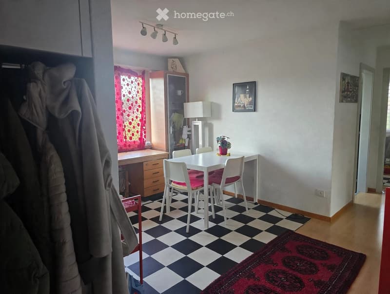 A well-lit room with a checkered floor, a white dining table with four chairs, a cabinet, a lamp, a picture frame, and a small plant on the table.