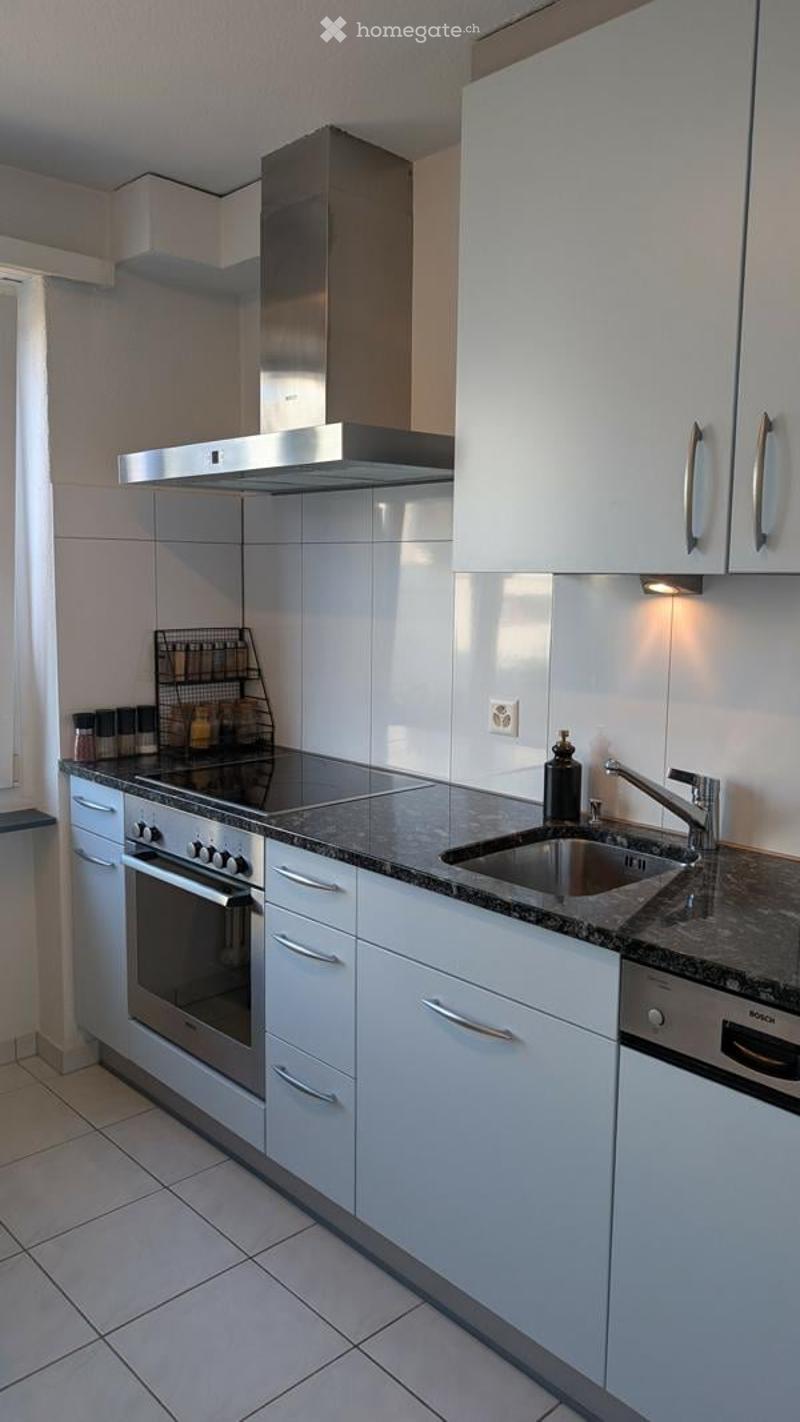 Modern kitchen with white cabinets, stainless steel appliances, granite countertop, and built-in oven and range hood.