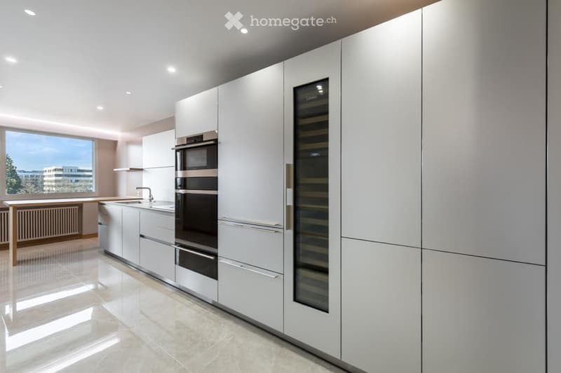Modern kitchen with white cabinets, stainless steel appliances, a wine cooler, and a large window offering a city view.