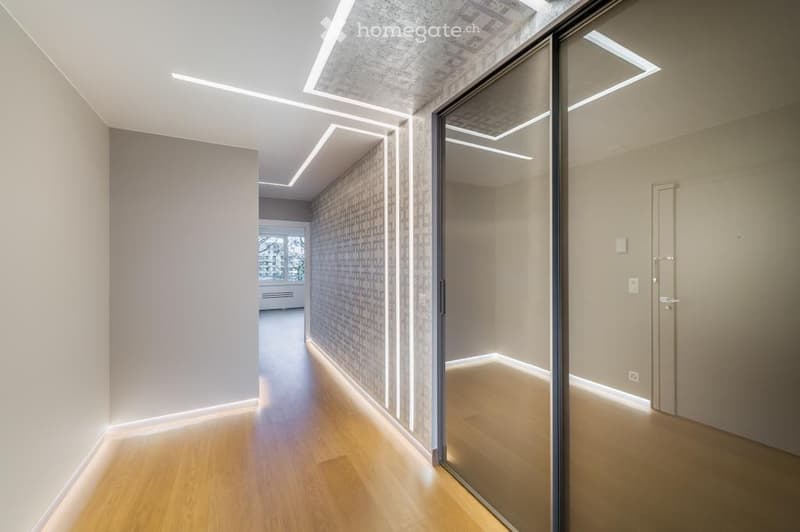 Modern hallway with wooden flooring, recessed lighting, and glass doors leading to adjacent rooms.