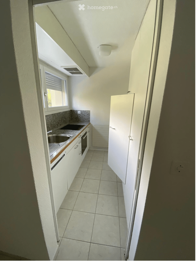 Modern kitchen with white cabinets, tiled floor, and stainless steel appliances including a sink and oven.