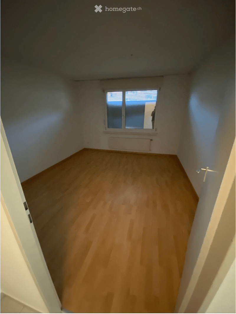 Empty room with light wooden flooring, white walls, and a single window with blinds. No furniture or equipment is present.