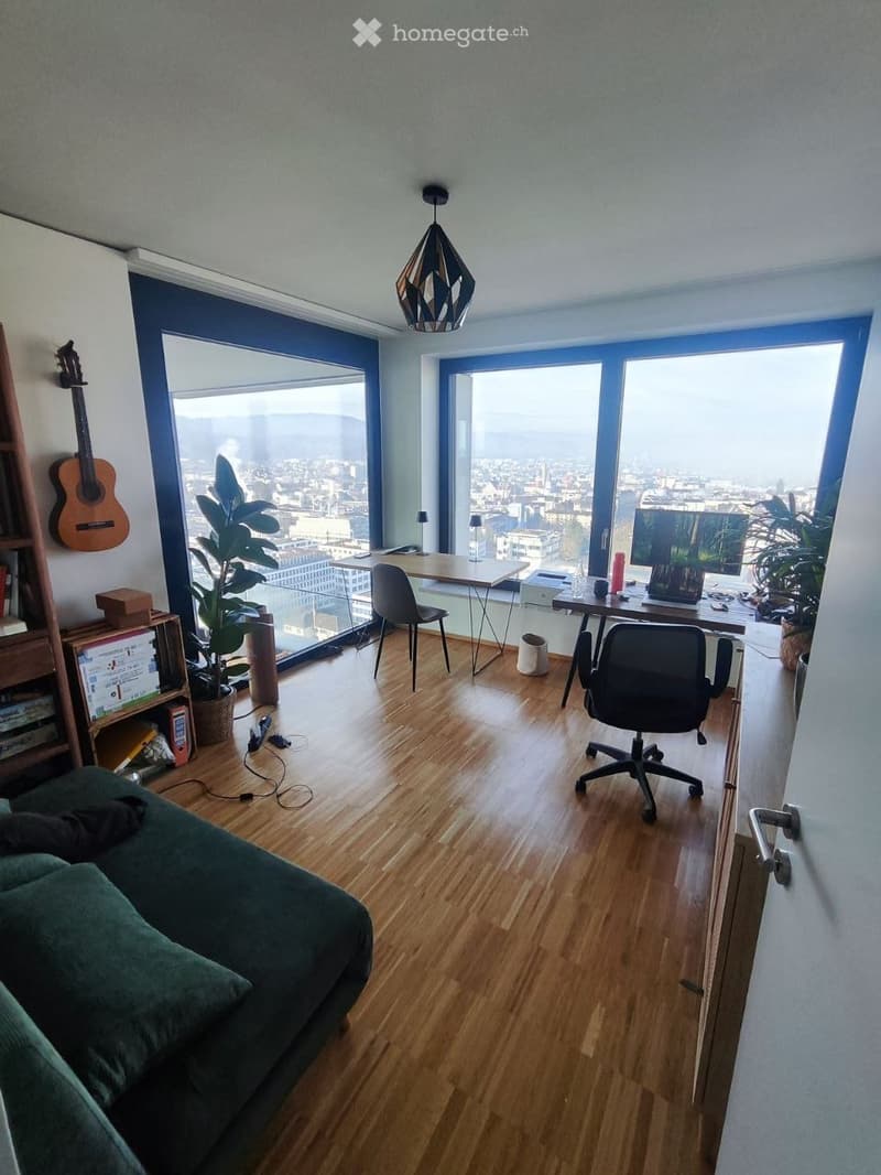 A modern, multi-functional room with a view of the city, featuring a sofa, desk with a laptop, chairs, a guitar, and plants.
