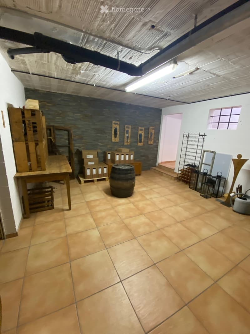 The room has tiled flooring, a wooden table, a wine barrel, wine racks, and several lanterns.