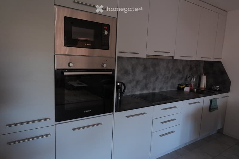 Modern kitchen with white cabinets, stainless steel appliances, and a black countertop.
