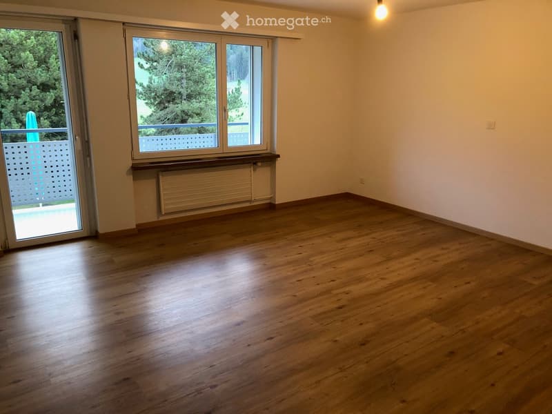 Empty room with wooden flooring, large windows, and a radiator under the windowsill.