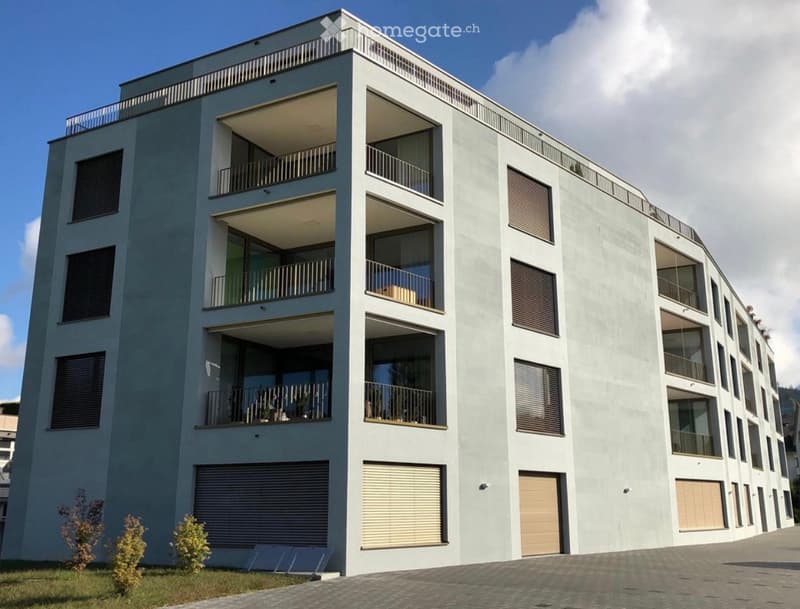 Modern multi-story residential building with balconies and large windows, featuring a sleek design and contemporary architecture.