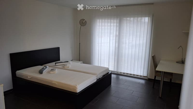 Modern bedroom with two single beds, a desk with a chair, and a floor lamp near a large window with vertical blinds.