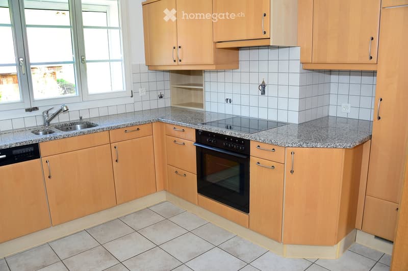Modern kitchen with light wooden cabinets, granite countertop, stainless steel sink and faucet, built-in oven, and dishwasher.