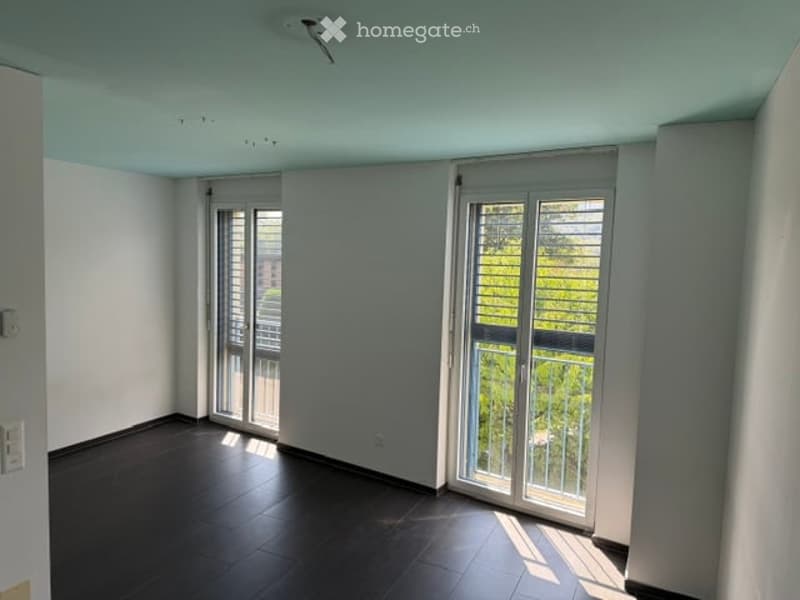 Empty room with dark tiled floor, white walls, and large glass sliding doors leading to a balcony.