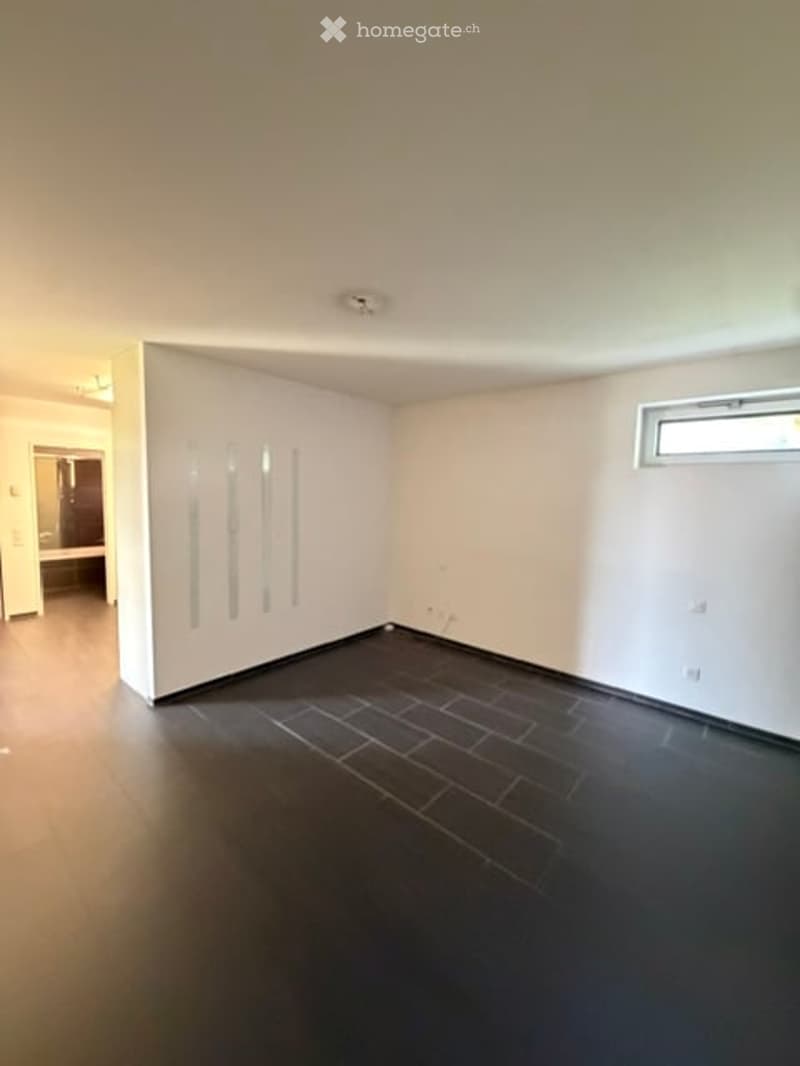 Empty room with white walls, dark tiled floor, and a built-in white cabinet. No furniture or equipment present.