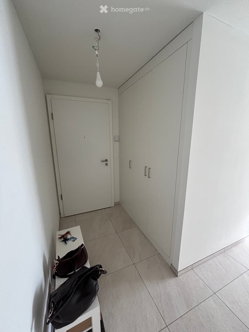 A small hallway with a white table holding two handbags, a door, and built-in white cabinets.