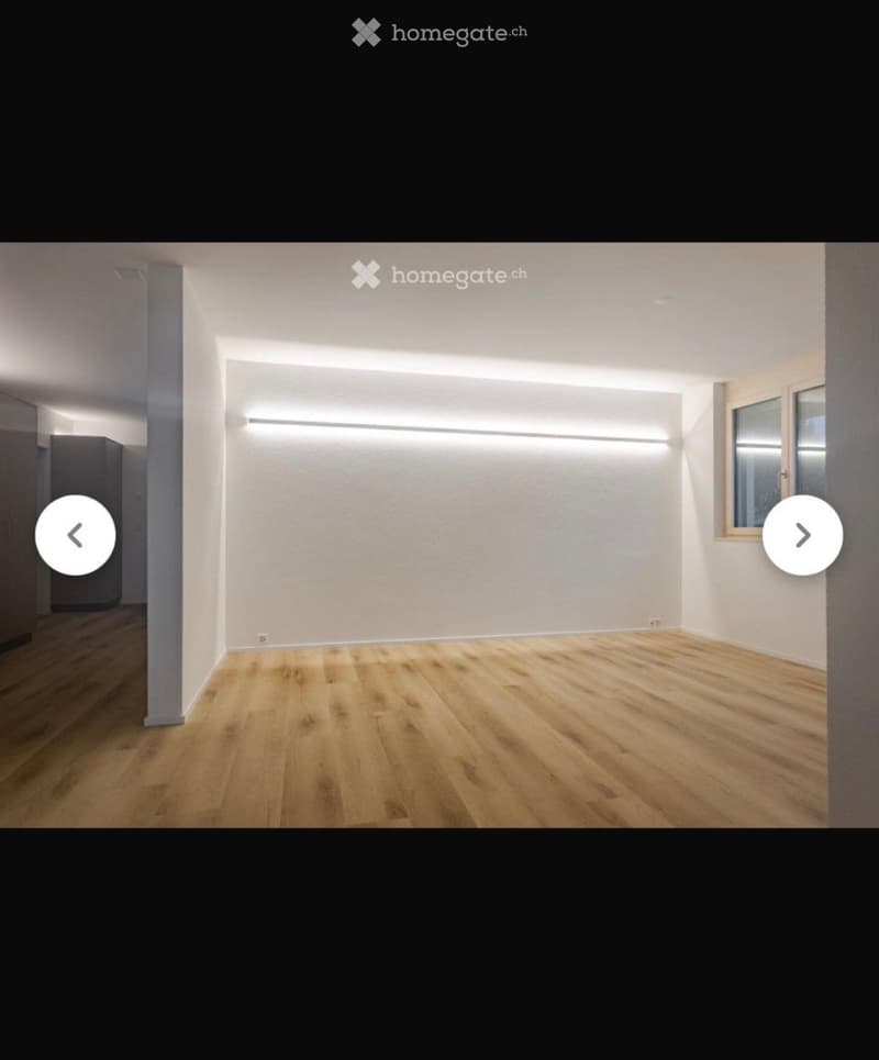 Empty room with light wooden flooring and white walls, featuring a large window and built-in LED lighting strips.