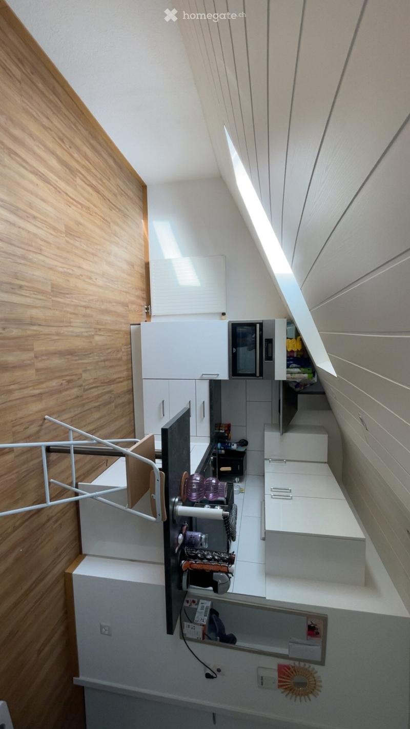 Compact kitchen with white cabinets, microwave, sink, and decorative items on the counter.