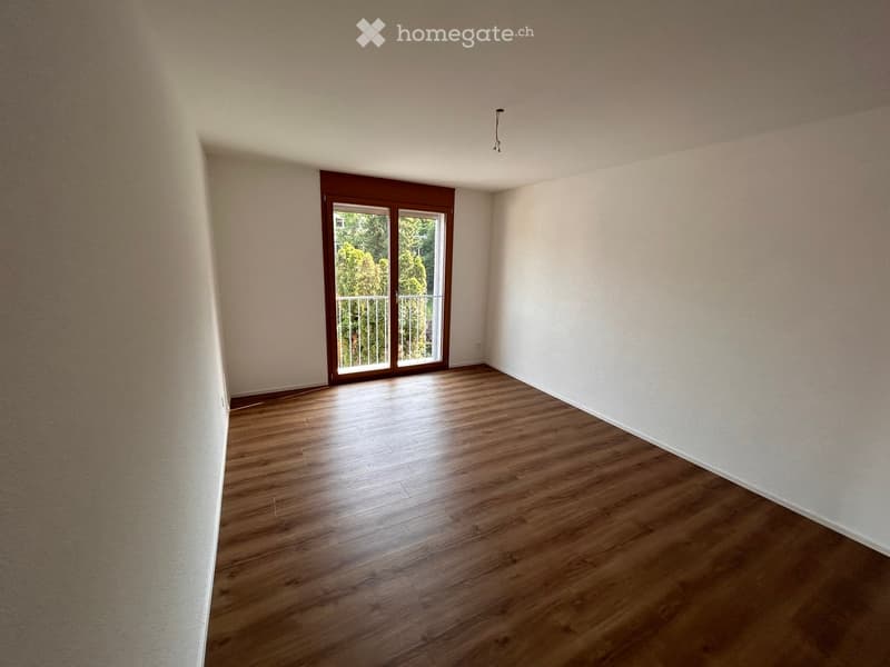empty room, wooden floors, white walls, sliding door to balcony, power outlet