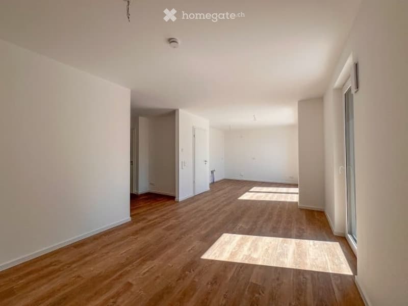 Empty room with wooden flooring, white walls, and large windows allowing natural light to enter. No furniture or equipment is present.