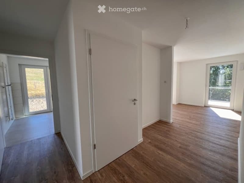 Empty room with wooden flooring, white walls, and large windows with blinds. No furniture or equipment present.