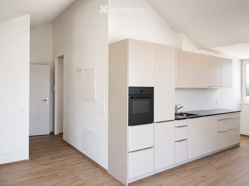 Modern kitchen with light-colored cabinets, a built-in oven, a sink with a faucet, and wooden flooring.