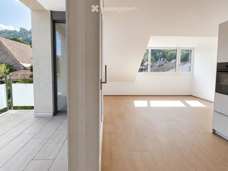 Empty room with wooden flooring and large windows offering a scenic view of the surrounding landscape. The space is unfurnished, with only the basic structure visible.
