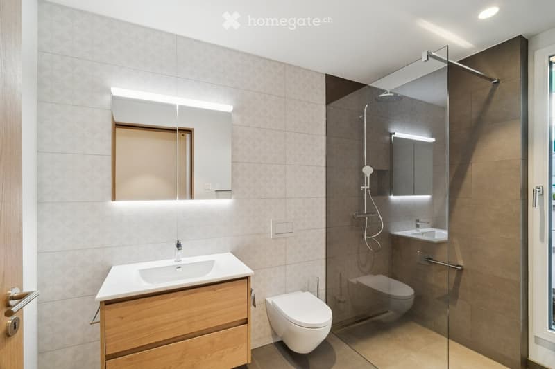 Modern white bathroom with shower, wooden vanity, and clean lines.