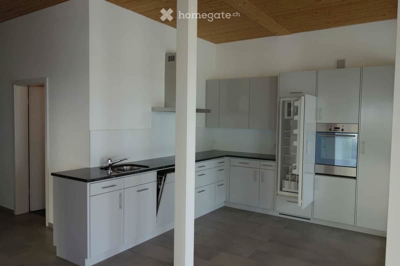 Modern kitchen with white cabinets, stainless steel appliances, and a black countertop. Features a sink with a faucet, an open refrigerator, and an oven.