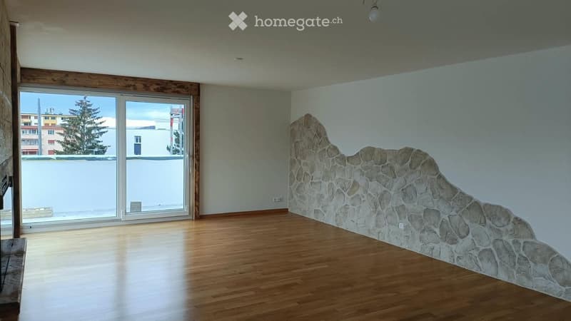 Empty room with wooden flooring, large sliding glass doors, and a stone accent wall. No furniture or equipment present.