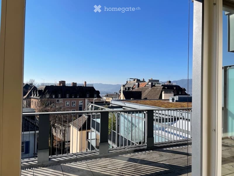 Balcony with metal railing, tiled floor, and a view of the cityscape and surrounding buildings.