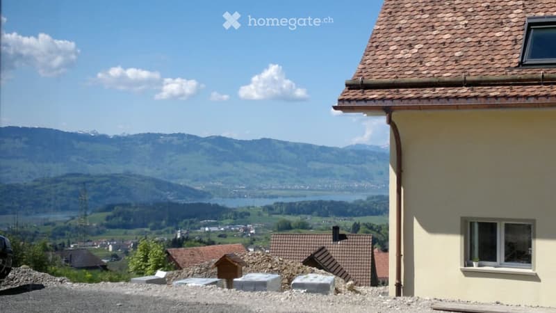 Building. View of a house with a tiled roof and a scenic mountain and lake backdrop.