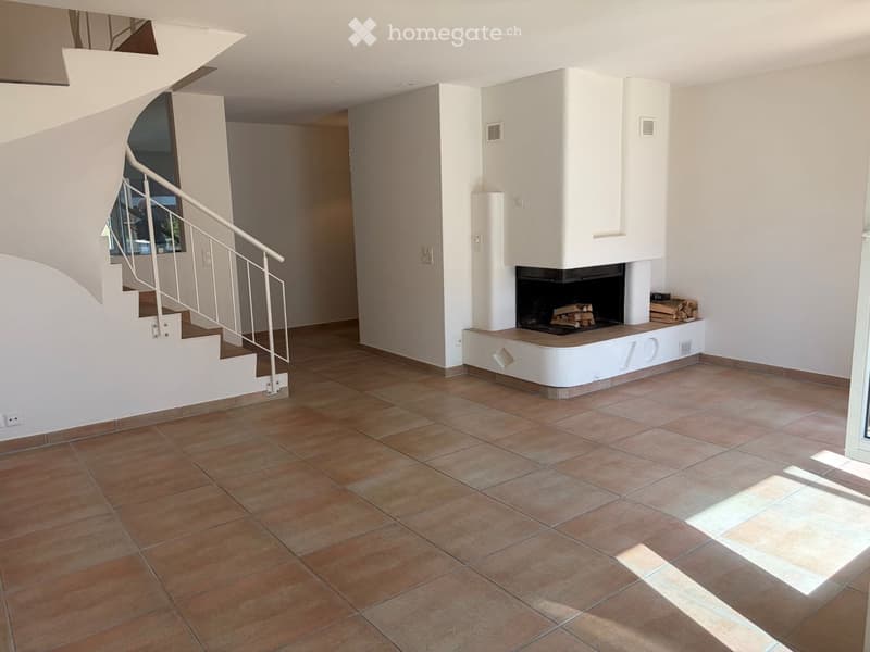 Bright hallway with tiled floor, white walls, staircase leading upwards, and a built-in fireplace with stacked firewood.