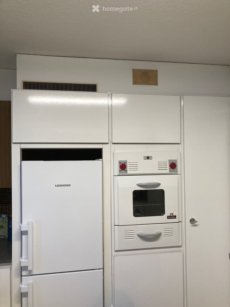White refrigerator and oven in a kitchen, with control panels and handles visible.
